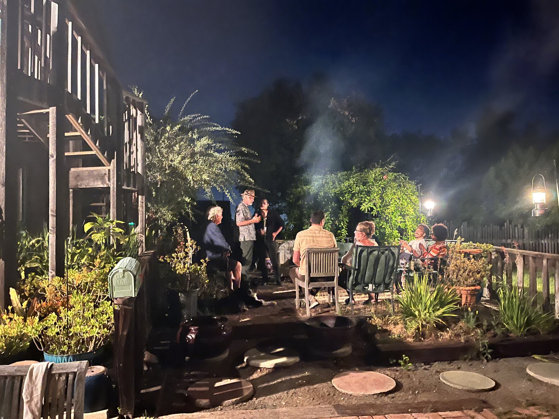 An outdoor table of shared dishes beside a wood-fired oven